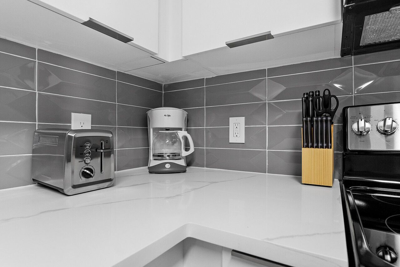 A modern kitchen with a toaster, coffee maker, and knife block on the counter.