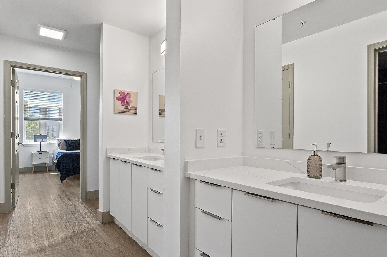 A modern bathroom with white fixtures, a large mirror, and a sink.