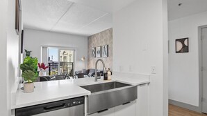 A modern kitchen with white cabinetry, stainless steel appliances, and a large window. - Midnight Marvel | Amazing City Views, Free Parking (Charlotte)