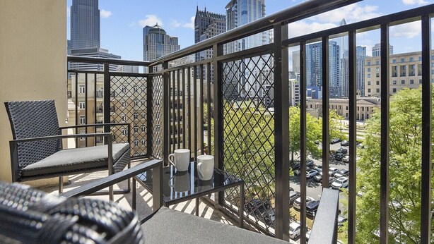 A balcony with a city view, a table with two white cups, and a chair. - Midnight Marvel | Amazing City Views, Free Parking (Charlotte)