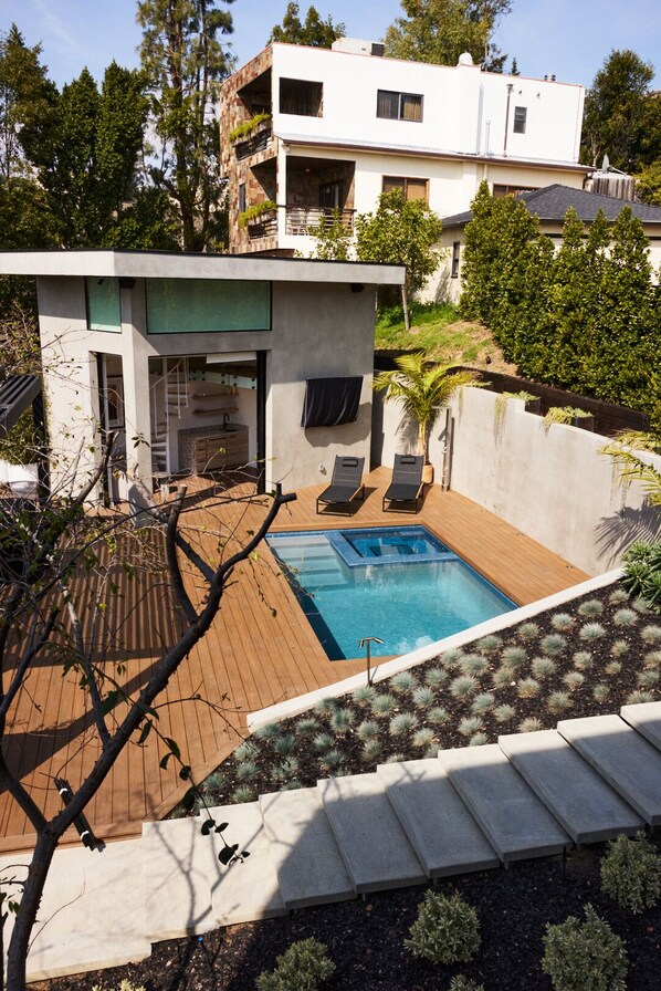Une maison moderne dotée d’une piscine, d’un espace extérieur aménagé et offrant une vue sur les bâtiments voisins.