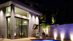 Un edificio moderno con piscina, porte in vetro e due poltrone relax.