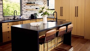 Una cucina moderna con isola centrale, sgabelli da bar, illuminazione a sospensione e mobili in legno.