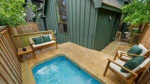 Un patio trasero con terraza de madera, una piscina pequeña y mobiliario para exteriores.