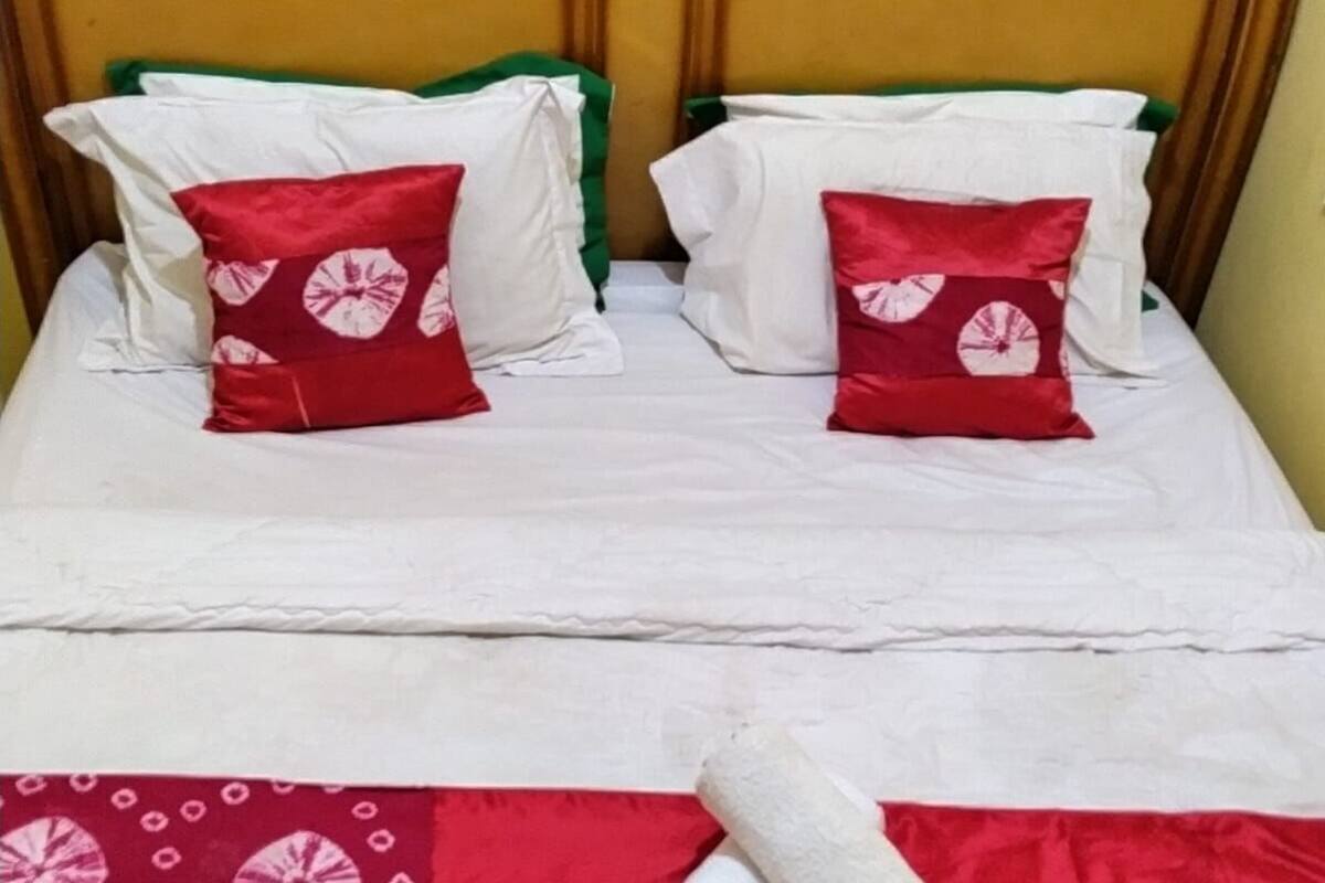 A bed with white bedding and two red pillows with a circular pattern.