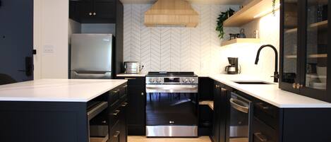 Een moderne keuken met een groot eiland, inbouwapparatuur en een backsplash met een herringbone-patroon.