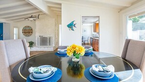 A dining area with a round table, blue placemats, and a vase of yellow flowers. - Family Vacation Home, Spa & Big Pool, Game Room, 8 minutes to Disney✨ (Anaheim)