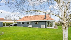 Une maison à deux étages, avec un toit recouvert de tuiles, un porche abrité et une voiture garée dans l’allée.