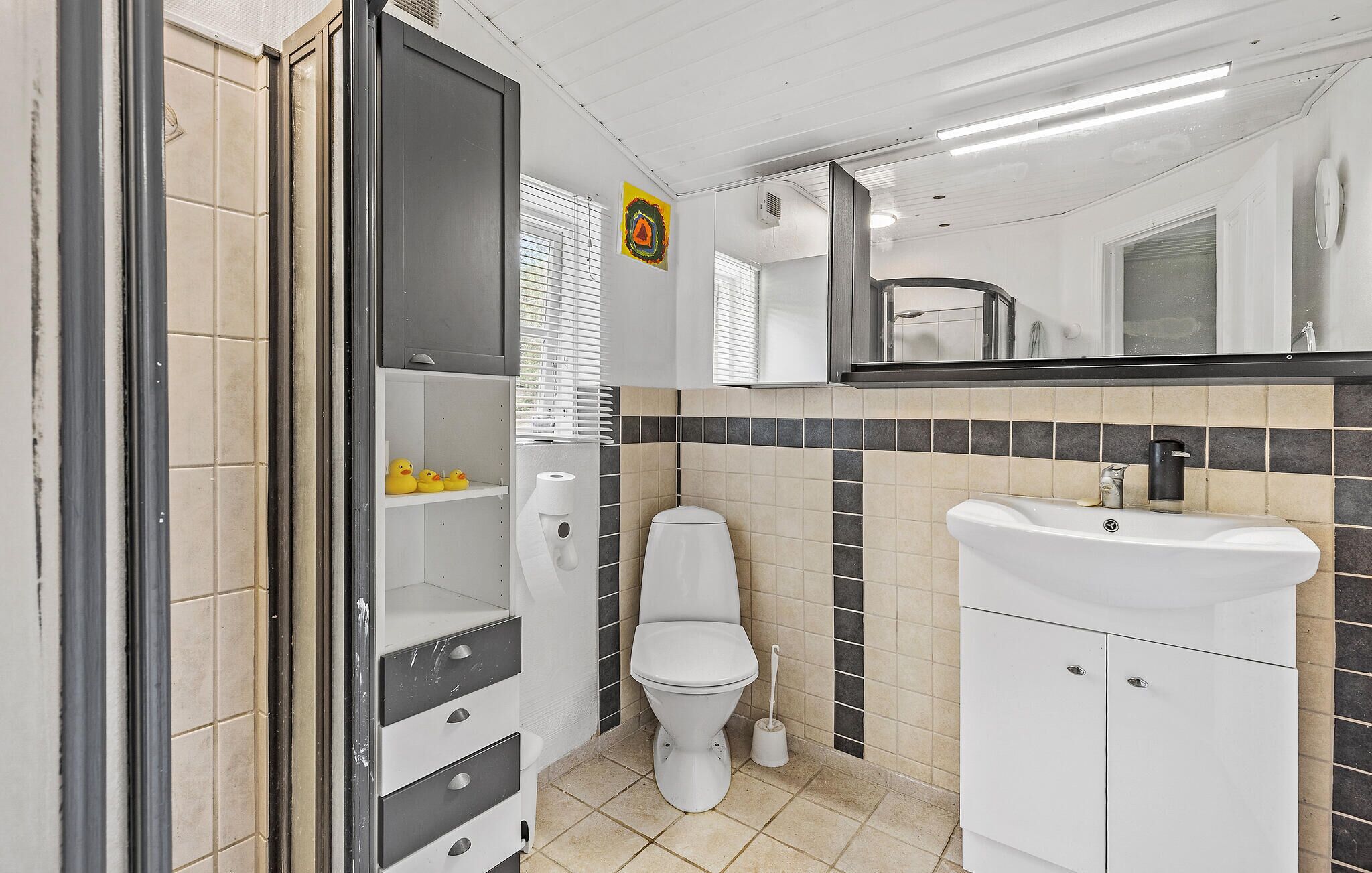Et badeværelse med toilet, vask og en hylde med gummianker.