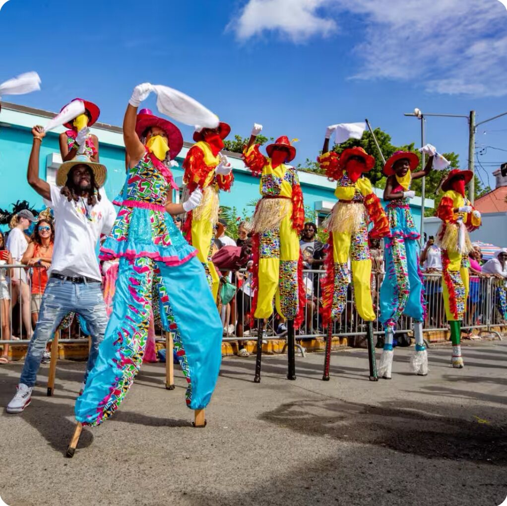 A street parade with performers in colorful costumes and a crowd watching.