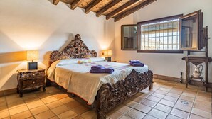 A bedroom with a large ornate bed, two bedside tables with lamps, a window with blinds, and a small table with a vase. - Cozy home in Salar with indoor swimming pool (Salar)