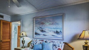 Une chambre à coucher avec un lit, une table de chevet, une lampe et un tableau accroché au mur.