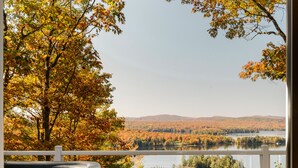 A spa area with a hot tub, wooden cabinets, and a view of a lake surrounded by autumn foliage. - Cozy cabin - lake view  (Lac-des-Îles)