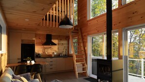 A cozy cabin interior with a kitchen, dining area, and a fireplace. - Cozy cabin - lake view  (Lac-des-Îles)