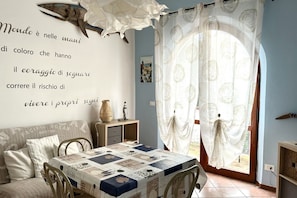 A room with a bed, a table with a quilt, a wall with a quote, and a window with curtains. - N284 - Numana, two-room apartment with terrace overlooking the sea (Numana)