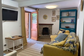 A living room with a sofa, a small table, a fireplace, and a television mounted on the wall. - S332 – Sirolo, apartment on the ground floor with courtyard and parking space (Sirolo)