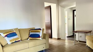 Un saló amb un sofà, una taula petita i una porta de fusta.