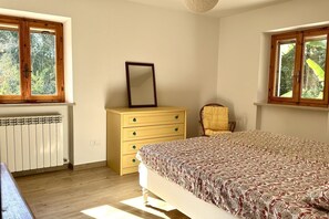 A bedroom with a bed, a dresser, a chair, and two windows. - S332 – Sirolo, apartment on the ground floor with courtyard and parking space (Sirolo)