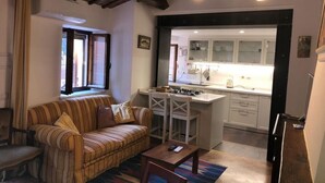 A living room with a sofa, a small table, and a kitchen area visible through an open doorway. - S333 – Sirolo, three-room apartment with terrace and parking space (Sirolo)