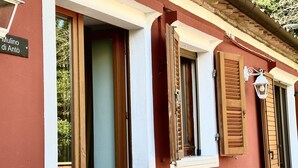 A building with a red facade, a sign reading 'Mulino di Anto', and wooden shutters on the windows. - S333 – Sirolo, three-room apartment with terrace and parking space (Sirolo)