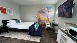 Ein modernes Hotelzimmer mit einem Bett, einem Schreibtisch, einem Stuhl und einem großen Gemälde vom Eiffelturm.