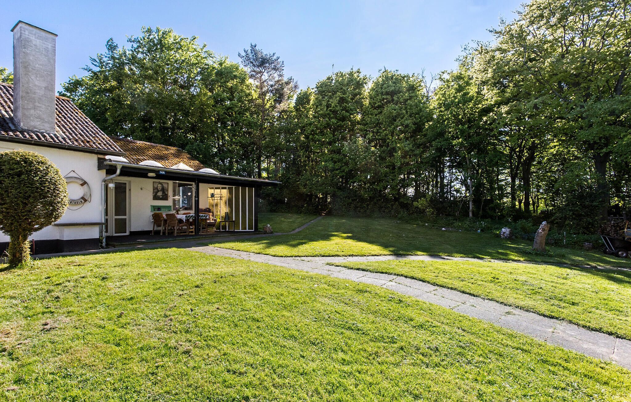 Une maison dotée d’un patio couvert, d’une pelouse et d’arbres en arrière-plan.