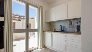 A kitchen with white cabinets, a countertop, and a view through a glass door. - GuestHost - Brand New Apartment with Pool and Terrace - Two Steps from the Beaches (Palau)