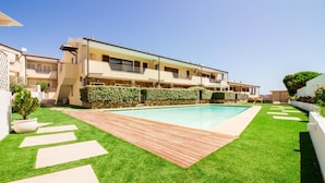 A modern villa with a swimming pool, a wooden deck, and a well-maintained lawn. - GuestHost - Brand New Apartment with Pool and Terrace - Two Steps from the Beaches (Palau)