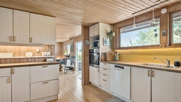 Une cuisine moderne avec des meubles en bois, un four encastré et une grande fenêtre qui laisse entrer la lumière naturelle.