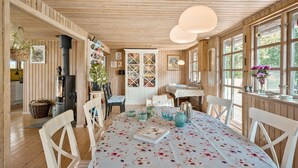 Un intérieur en bois avec une table à manger dressée pour quatre personnes, entourée de chaises blanches.