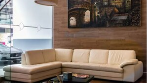Ein modernes Wohnzimmer mit einem beigefarbenen Ecksofa, einem Couchtisch und einem großen Gemälde einer alten Brücke an der Wand.