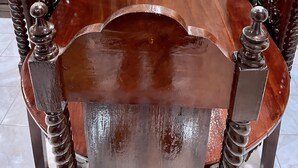 A wooden dining table with ornate chairs, a decorative backrest, and a mirror on the wall.