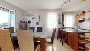 Una cucina moderna con isola centrale, mobili in legno e zona pranzo con sedie in vimini.
