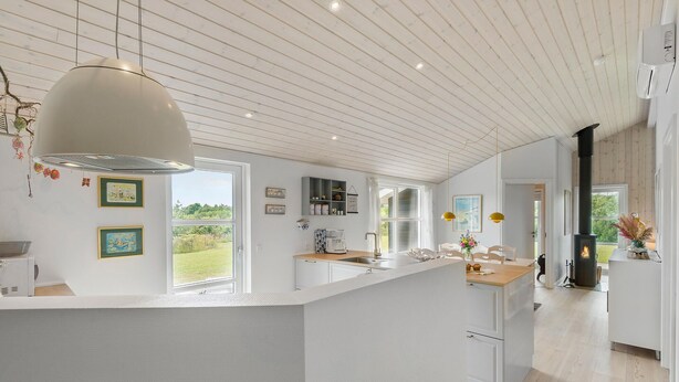 A modern kitchen with a central island, white cabinetry, and a large pendant light. - Amazing home in Tarm with sauna (Tarm)