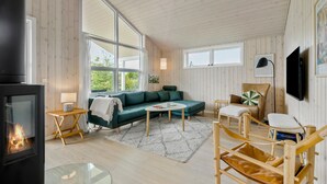 A cozy living room with a sofa, a chair, a small table, and a fireplace. - Amazing home in Tarm with sauna (Tarm)