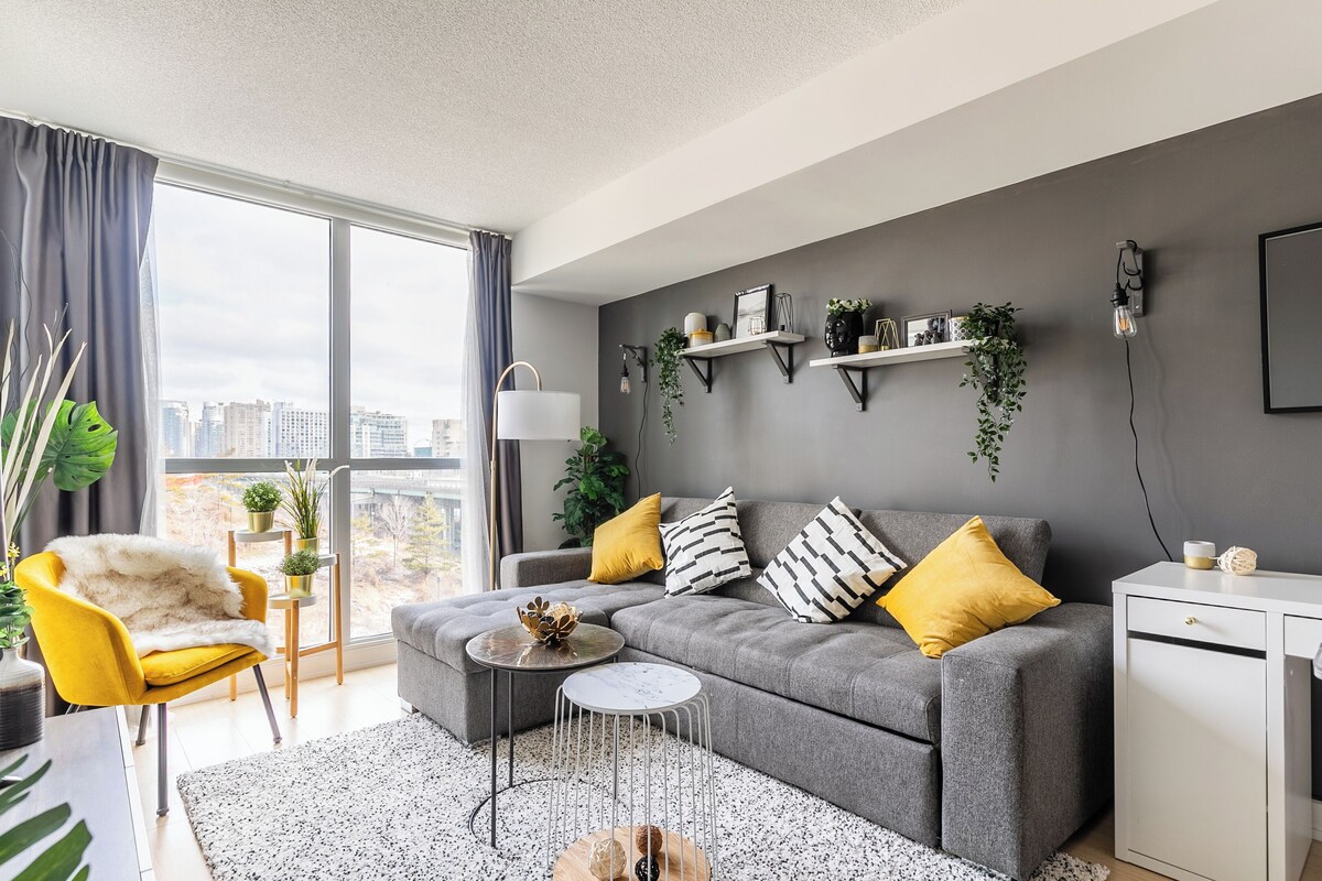 A modern living room with a grey sofa, yellow armchair, and a white cabinet.