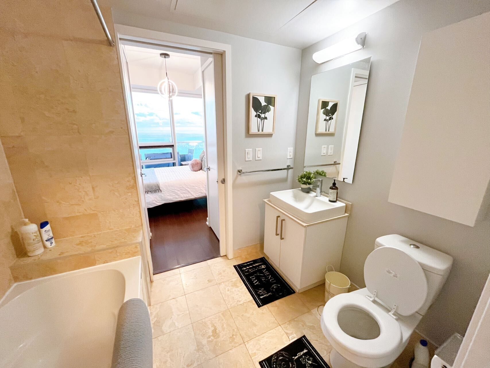 Un baño moderno con bañera, inodoro y lavamanos. Se ve una puerta que da a un balcón con vistas.