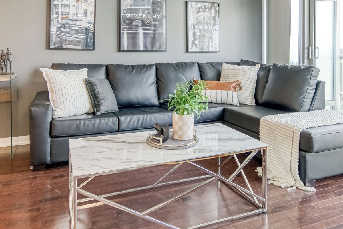 A modern living room with a grey sofa, a marble coffee table, and framed artwork on the wall.
