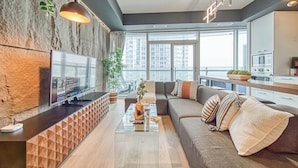 A modern living room with a TV, sofa, and coffee table. - SkyTree Modern Suites (Toronto)