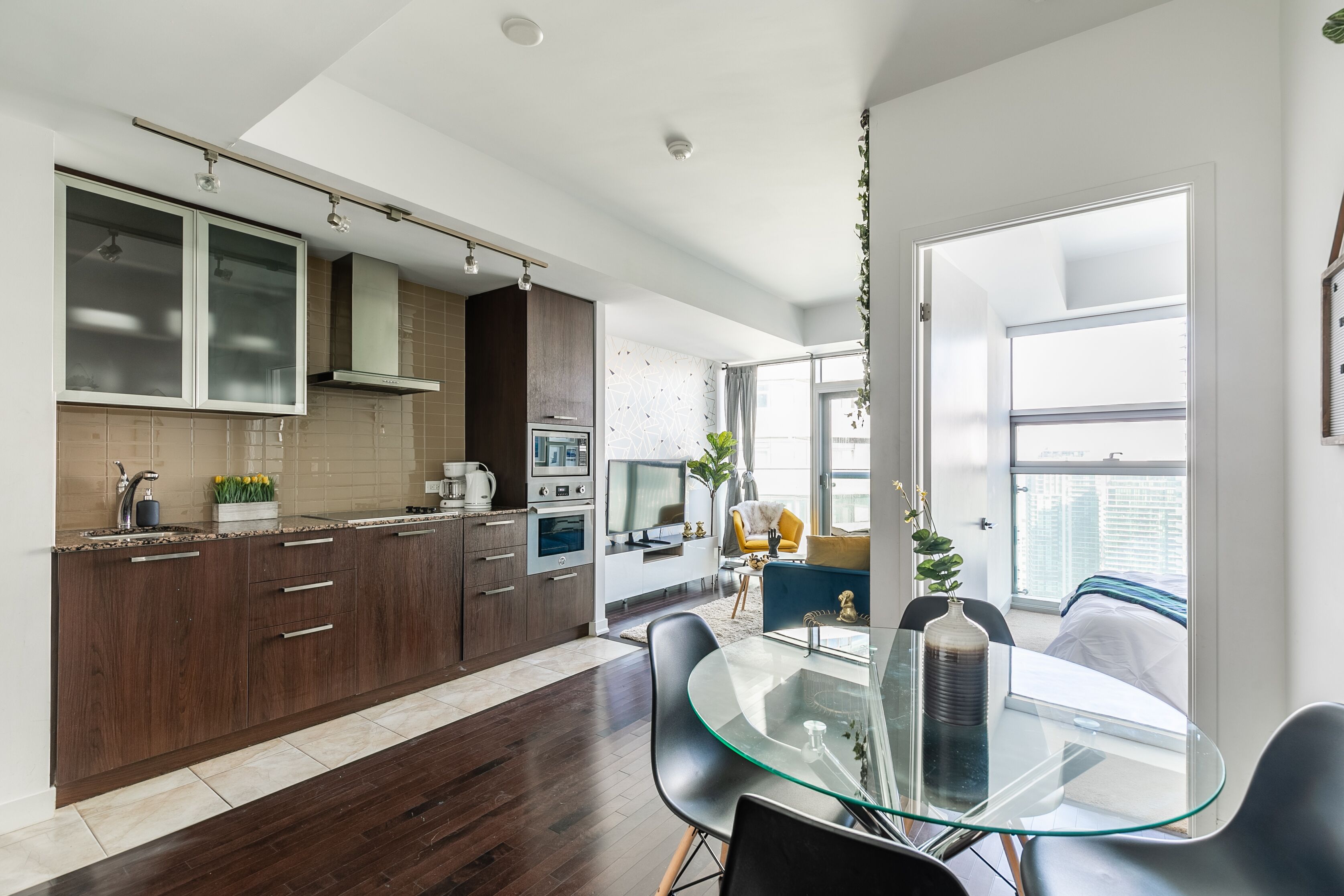 Een moderne keuken met donkerhouten kastjes, een glazen eettafel en een groot raam met uitzicht op de stad.