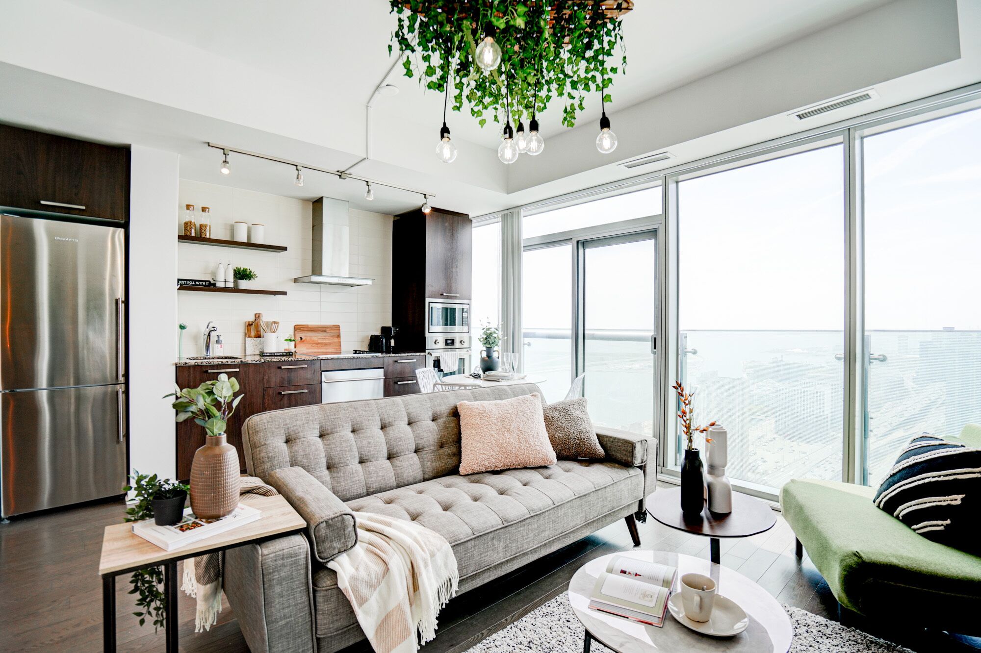 A modern living room with a sofa, coffee table, and a view of the city through large windows.