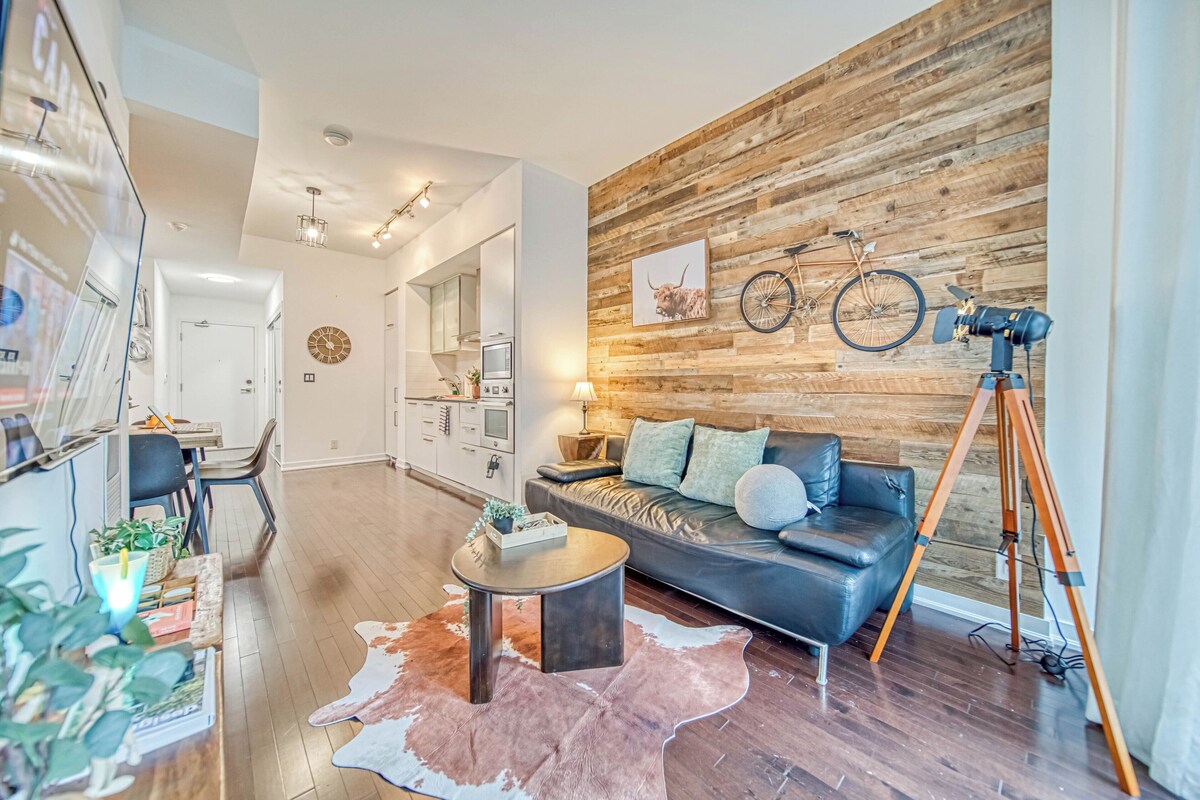 A modern living room with a leather sofa, a round coffee table, and a wooden accent wall.