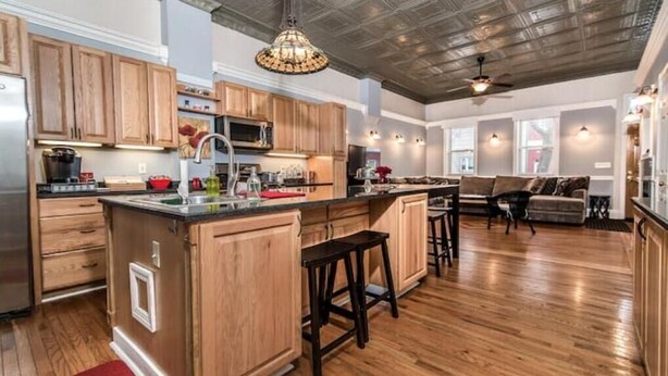 A spacious kitchen with wooden cabinets, a central island, and a dining area with a sofa and chairs. - Beautiful High-End 4 Bed 3 Bath House, Sleeps 15! (Pittsburgh)