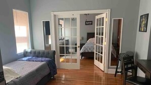 A bedroom with a bed, a desk, and a chair. There are two doors leading to another room. - Beautiful High-End 4 Bed 3 Bath House, Sleeps 15! (Pittsburgh)