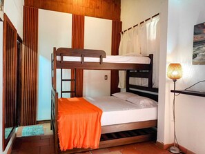 A bunk bed room with a wooden headboard, a bedside table with a lamp, and a window with curtains. - Hotel La Palma Centro Histórico (Santa Marta)
