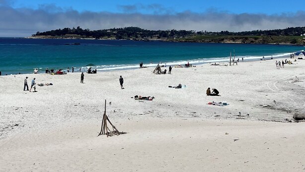 A wide sandy beach with clear blue water and a distant tree-covered hill. - Charming Cottage in Carmel-by-the-Sea. Blocks from downtown and the beach! (Carmel-by-the-Sea)