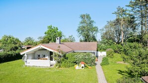 A small house with a sloped roof and a chimney, surrounded by lush greenery and trees. - Cozy home in Slagelse with WiFi (Slagelse)