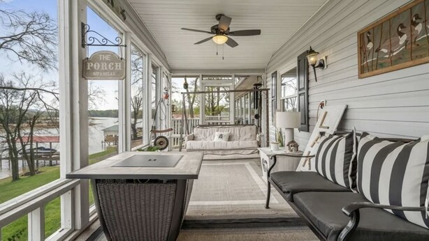 A covered porch with a dining table, a sofa, and a wicker chair. - Welcome to our lake house on the beautiful Hiwassee River! (Calhoun)