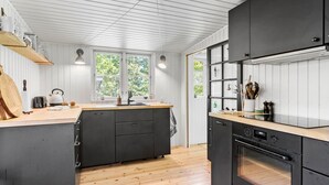Eine moderne Küche mit einer zentralen Kochinsel, Holzböden und großen Fenstern.