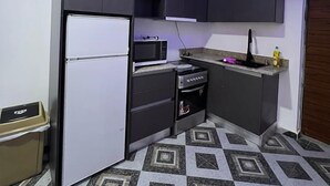 Una cocina compacta con armarios oscuros, un refrigerador, un microondas, una estufa y un lavaplatos.